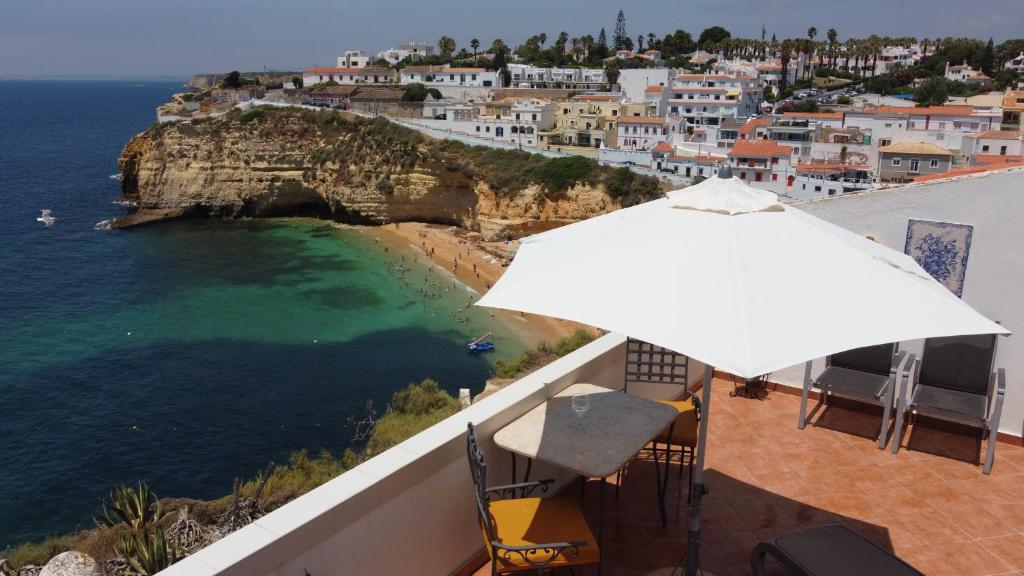 a balcony with an umbrella and a view of the ocean at CastelloHouse, The Best Sea View, in front of Carvoeiro beach in Carvoeiro