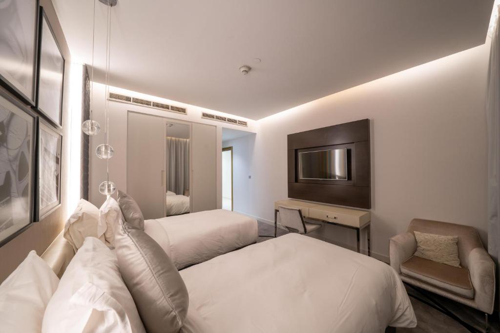 a hotel room with two beds and a television at DAMAC Royal Two Bedroom Apartment Al Olaya in Riyadh