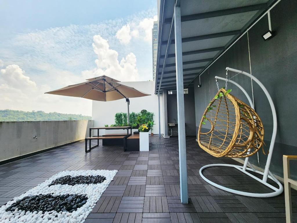 a balcony with a bench and an umbrella and a swing at Savanna Executive Garden by Define Suite in Kampung Dengkil