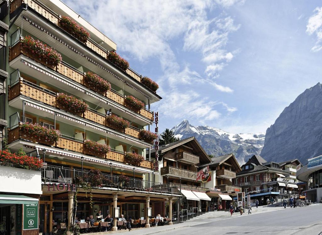 un edificio en una calle con montañas en el fondo en Hotel Central Wolter - Grindelwald, en Grindelwald