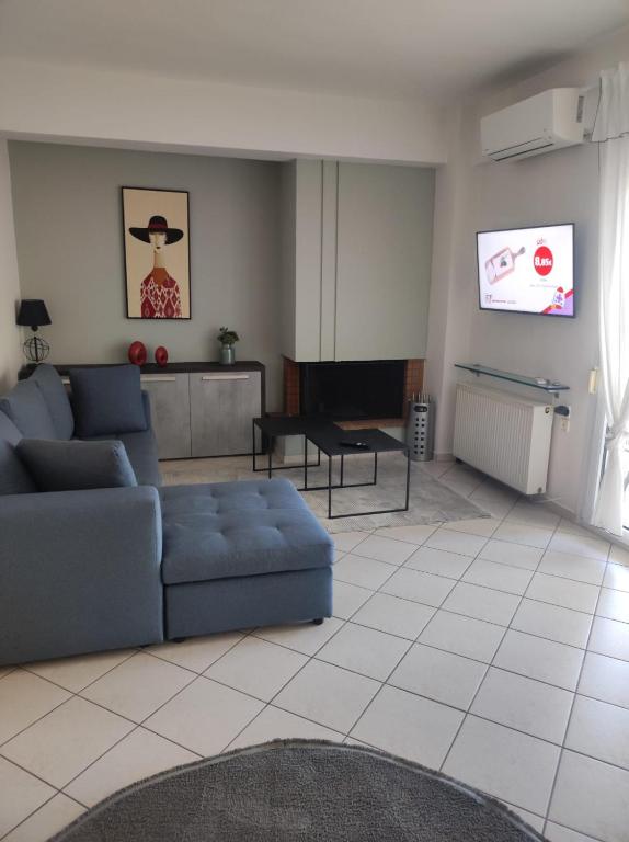 ein Wohnzimmer mit einer blauen Couch und einem Fernseher in der Unterkunft ZenPoint in Larisa