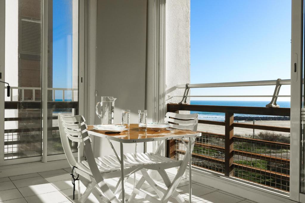 une table et des chaises sur un balcon avec vue sur l'océan dans l'établissement Marelia by POM, pkg, logia, au Cap d'Agde