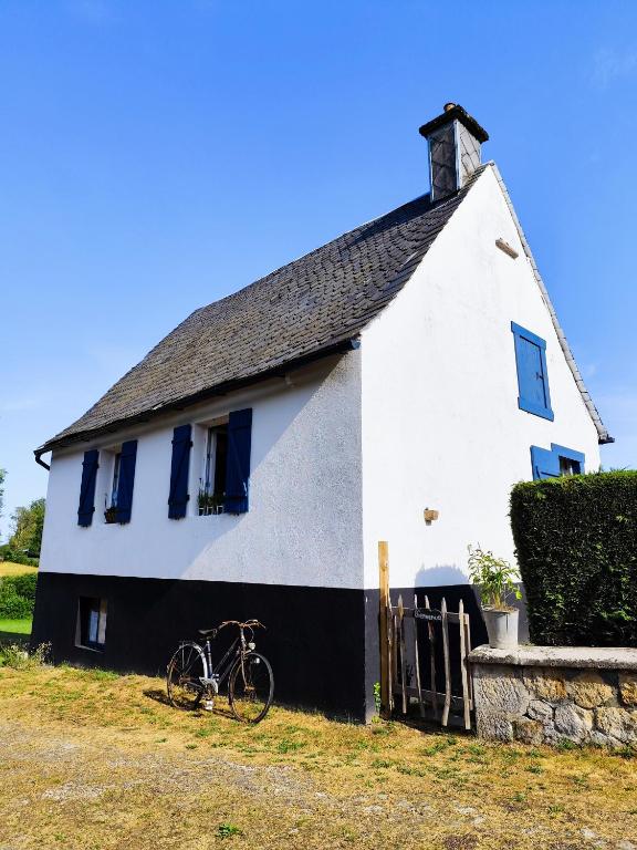 un vélo garé devant une maison blanche dans l'établissement Le Cottage, à Messeix