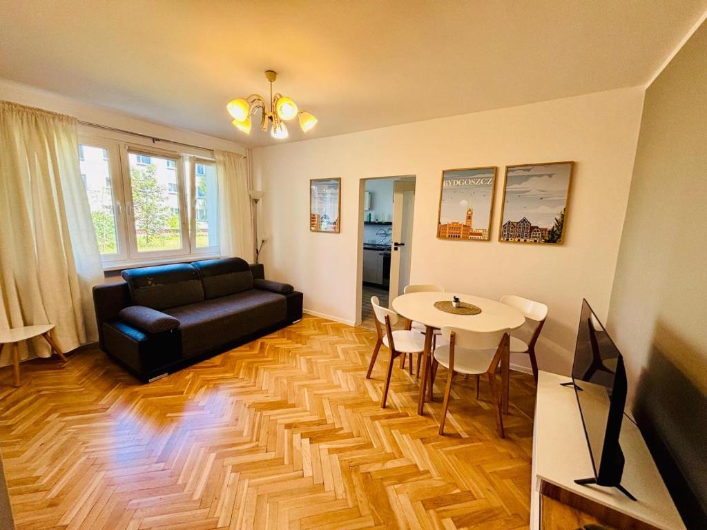 a living room with a black couch and a table at Apartament Kasprzaka in Bydgoszcz