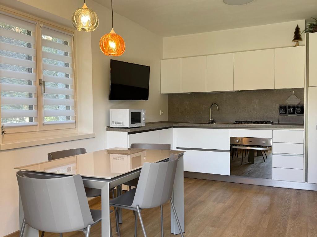 a kitchen with a table and chairs and a tv at Moderno appartamento con giardino in Carisolo