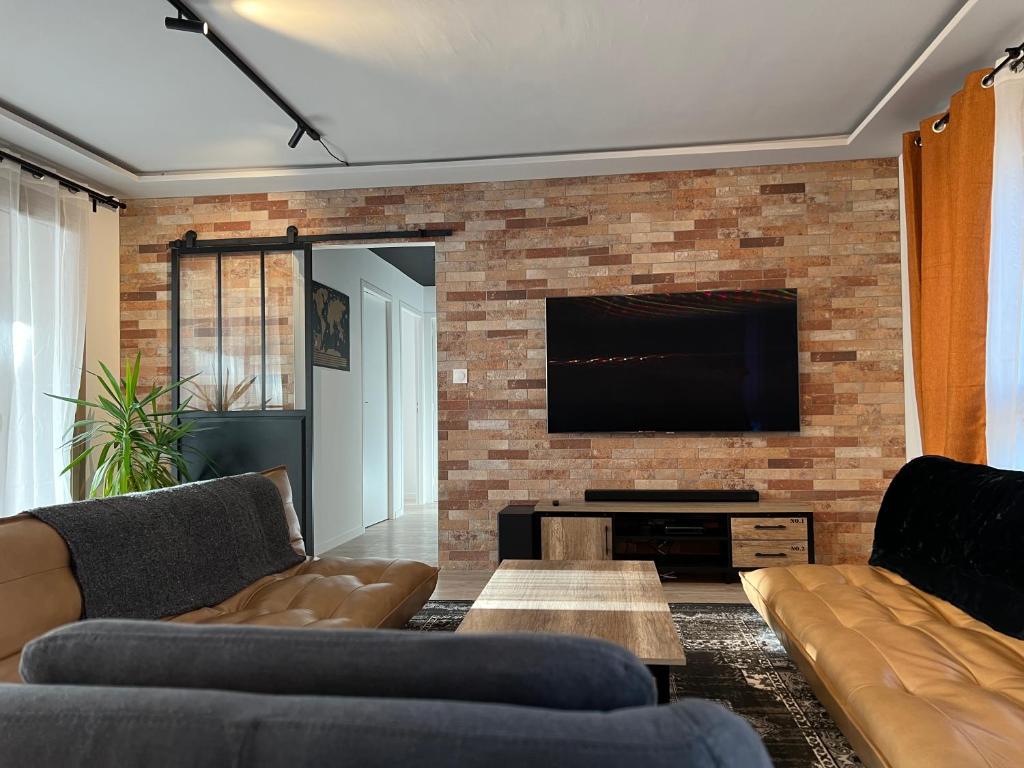 - un salon avec deux canapés et une télévision sur un mur en briques dans l'établissement Grand appartement cosy neuf et bien équipé, à Bordeaux