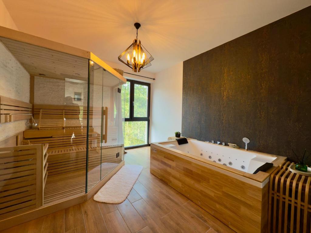 a large bathroom with a tub and a glass wall at Vila Ferdinand Spa and Retreat in Sinaia