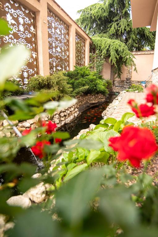 a garden with red flowers and a pond at Rosiem House in Techirghiol