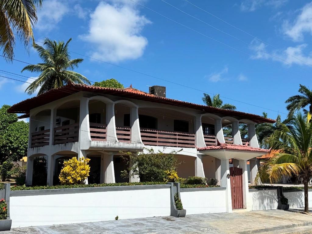 un gran edificio blanco con palmeras en el fondo en Casarão do Lago, en Salinópolis