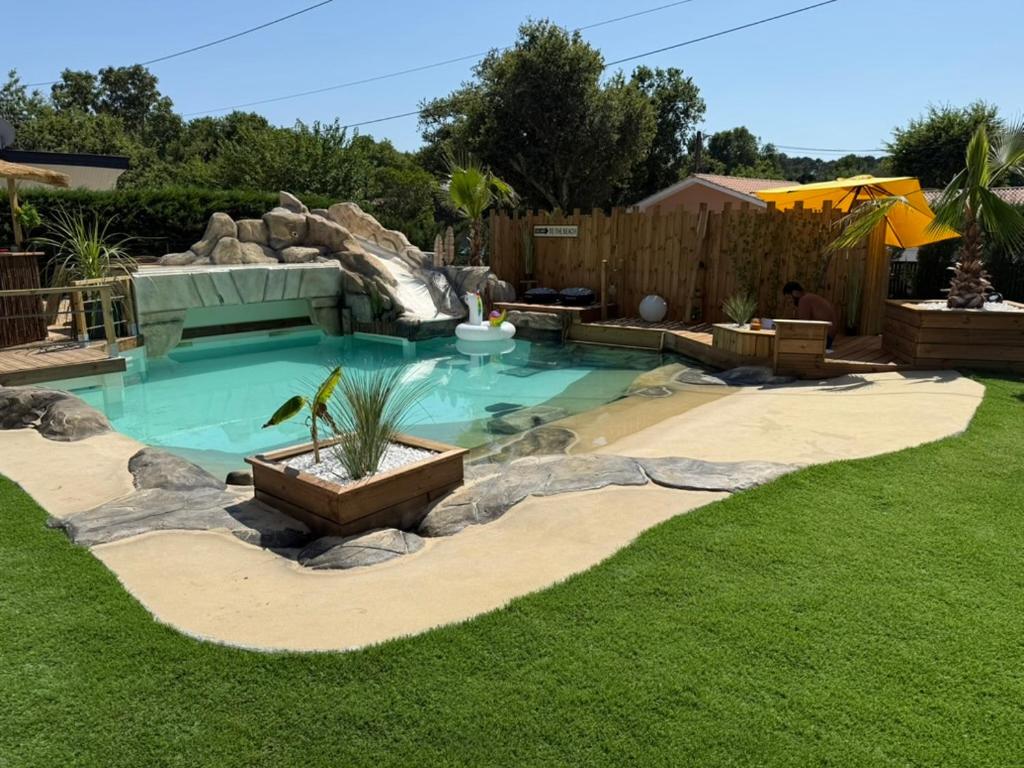 a swimming pool with a waterfall in a yard at Maison du Lac avec Lagon, Spa de Nage, Jacuzzi in Biscarrosse