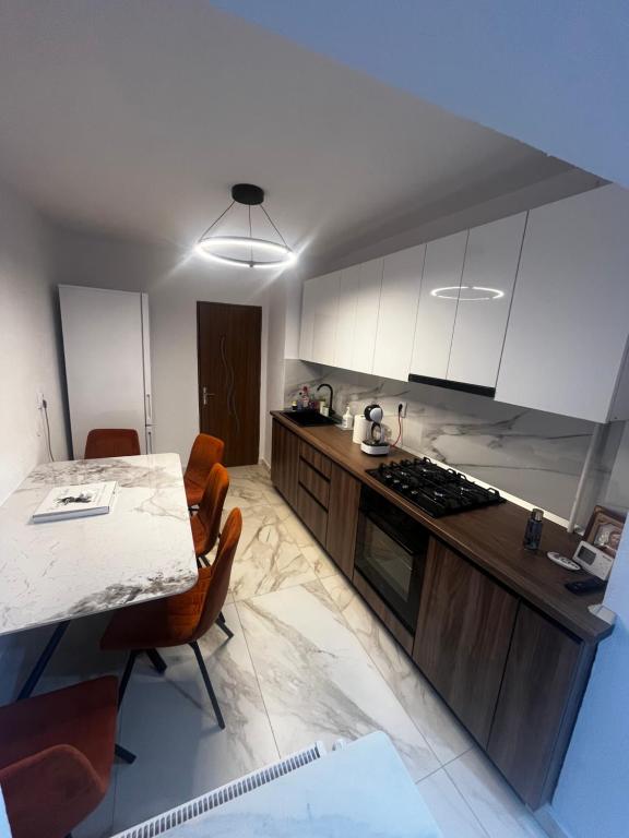 a kitchen with white cabinets and a table with chairs at Noble Stay in Curtea de Argeş