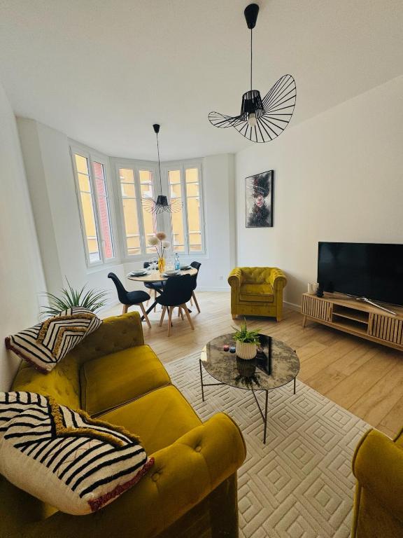 a living room with a yellow couch and a tv at Chez Rose Appartement cosy centre ville in Vichy