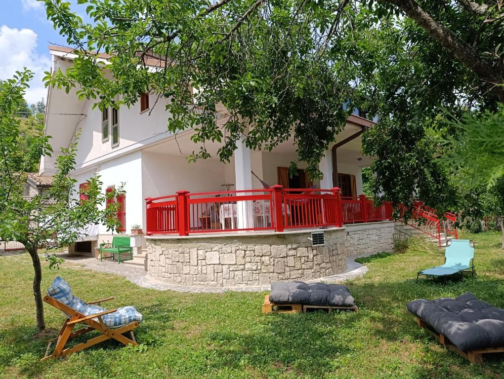 una casa con un ponte rosso e sedie nel cortile di Casa BnB Pappappero Monti della Laga a Fioli