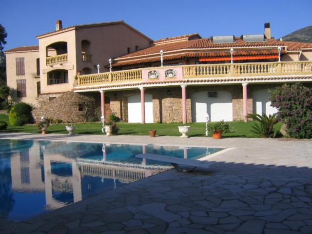 - un grand bâtiment avec une piscine en face dans l'établissement Auberge U Licettu, à Cuttoli-Corticchiato