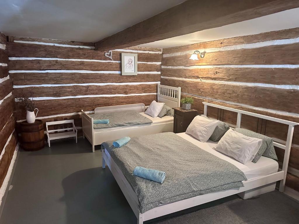 - une chambre avec 2 lits et un mur en bois dans l'établissement Bezva relax Bezděz, à Luka