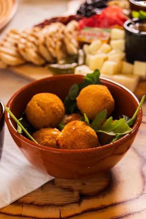 A bowl of golden fried bites set among fruit, cheese and other breakfast dishes.