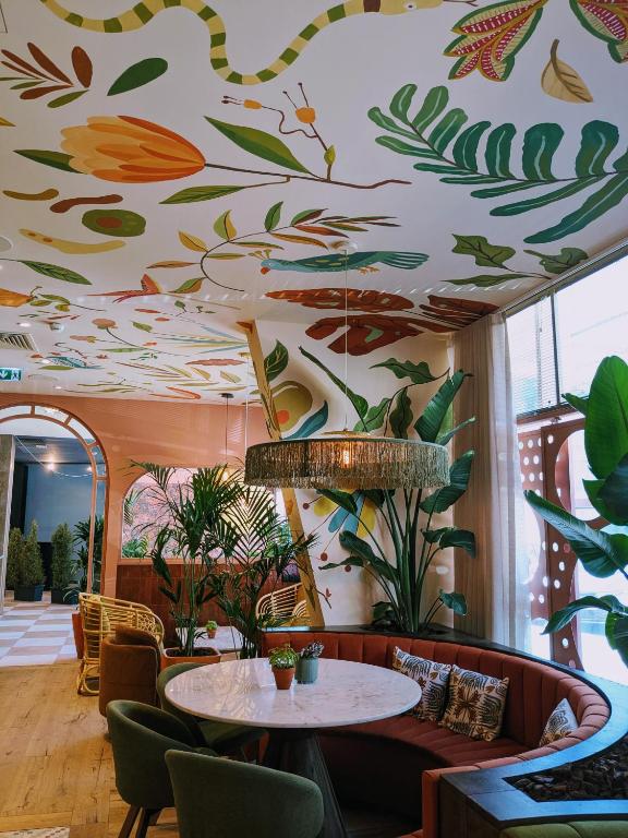 A botanical hotel lounge with a curved banquette beneath a painted ceiling.
