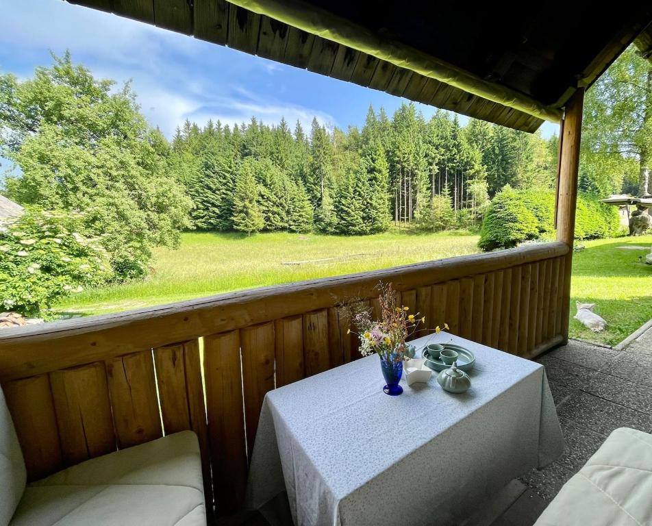 a table with a vase of flowers on a porch at Vacation cottage house Enya in Koprivnik v Bohinju