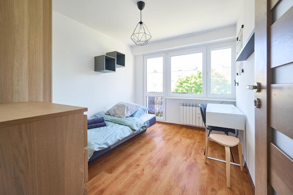 a bedroom with a bed and a desk and a window at Korczak Centrum Olsztyn in Olsztyn