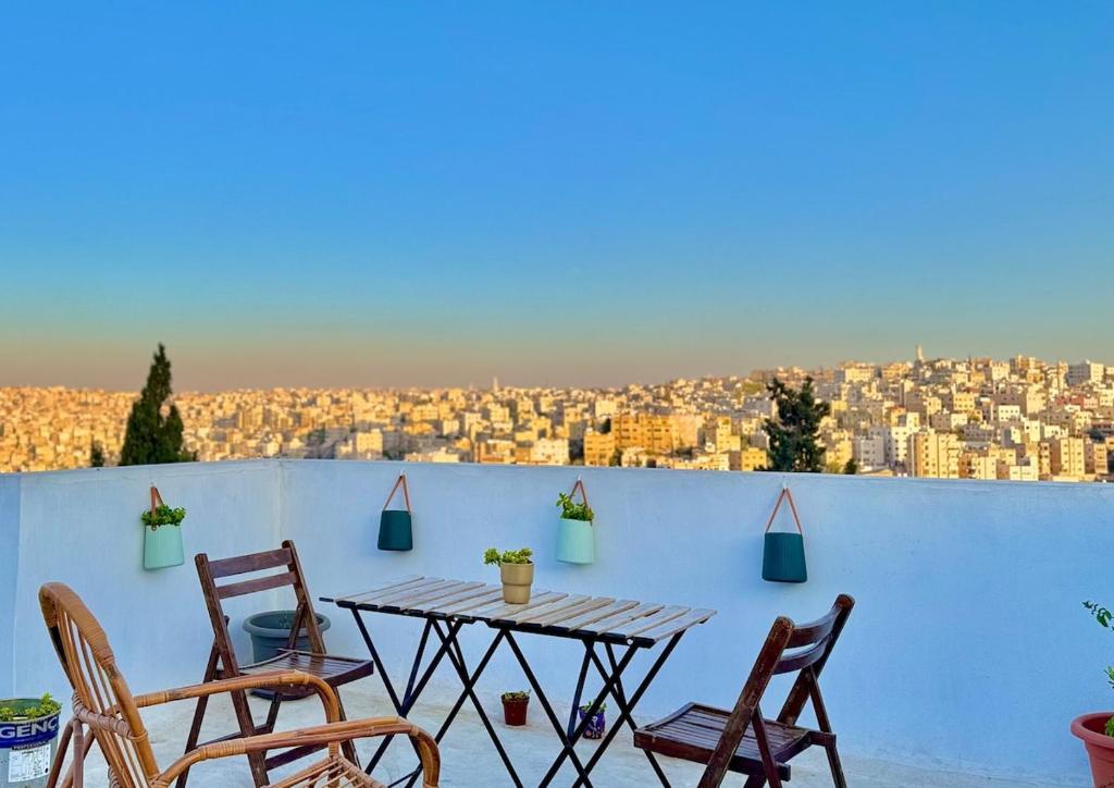 a table and chairs on a balcony with a view of a city at Modern Apartment in Prime Location - Jabal Amman in Amman