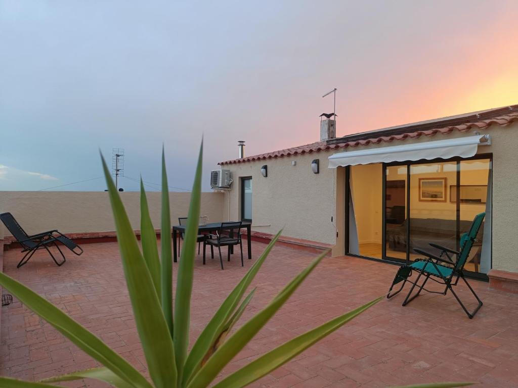 帕劳·萨巴尔德拉Sunny Relaxing Penthouse Costa Brava, Sea & Mountain Views, Huge Terrace, Fiber 1GB的建筑物前有椅子和桌子的露台