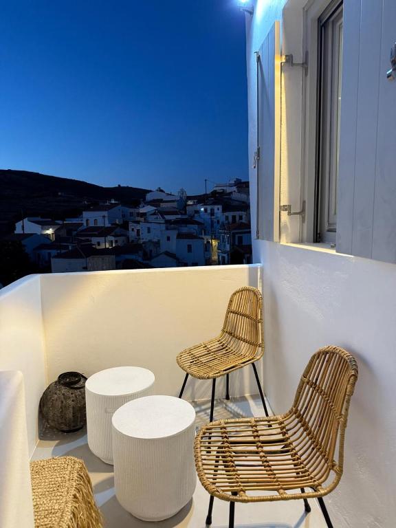 two chairs and tables on a balcony with a view at Ola House Dryopida Kythnos in Dhriopís