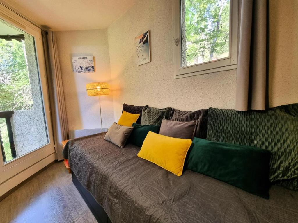 - une chambre dotée d'un lit avec des oreillers jaunes et verts dans l'établissement Résidence Les Roches Blanches - Studio niché au coeur des Mélèzes les Orres 1650 MAE-6861, aux Orres