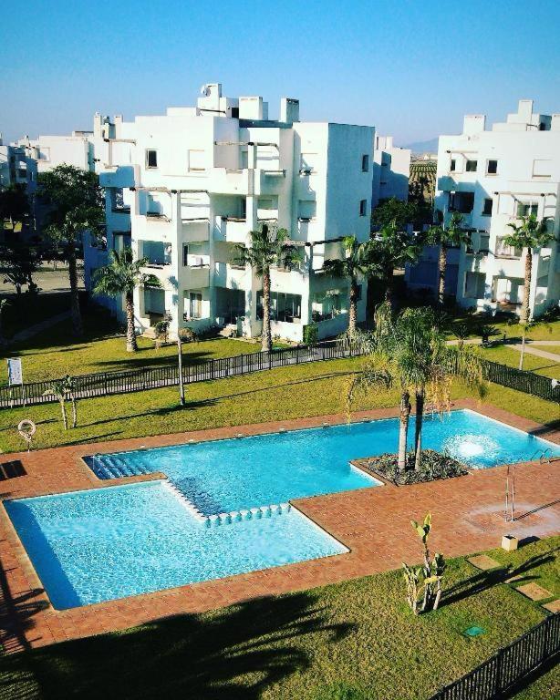 a swimming pool in front of a large building at Torres in Roldán