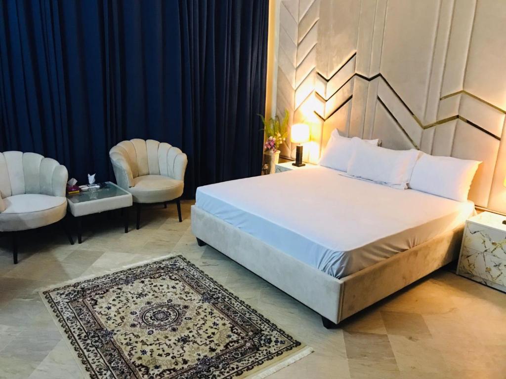 Un dormitorio con una cama grande y dos sillas. en Dazzy Dream Guest Houses, en Islamabad