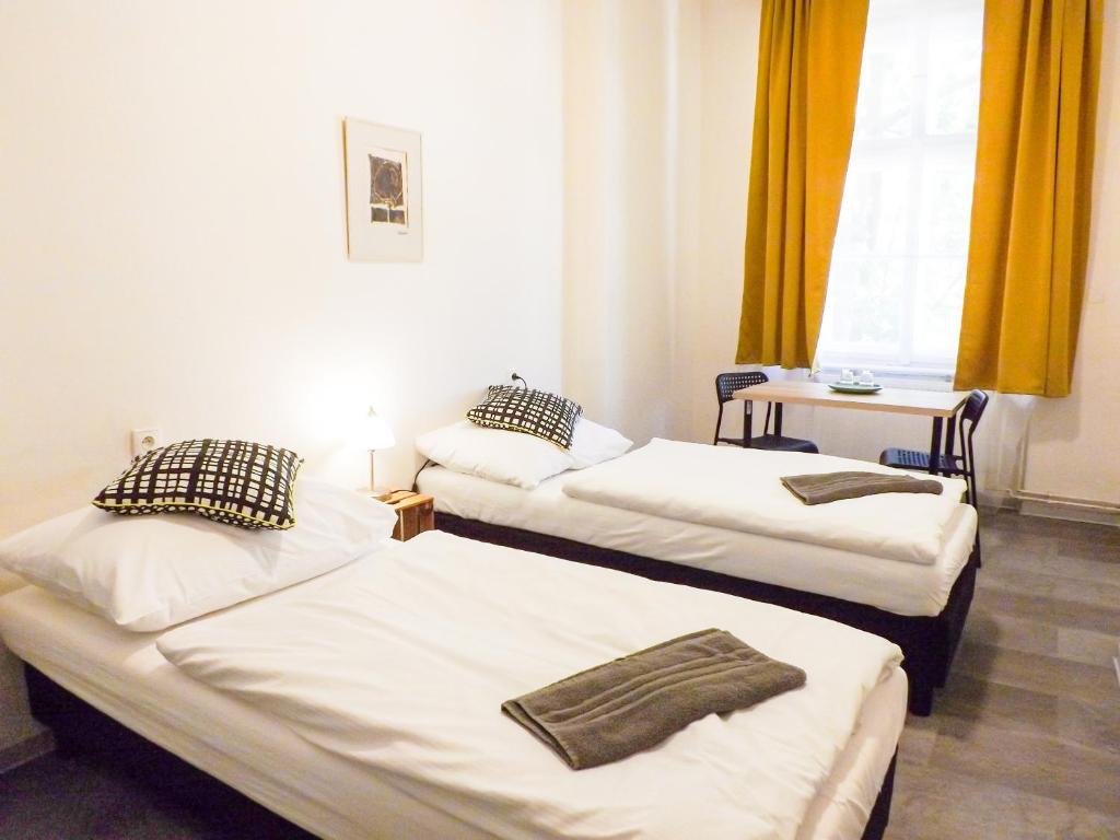 2 łóżka w pokoju z żółtymi zasłonami w obiekcie Friends on the Road D4 Prague w Pradze