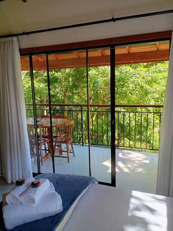 a bedroom with a bed and a balcony with a table at Lindo Chalé a 7 minutos do Centro in Domingos Martins