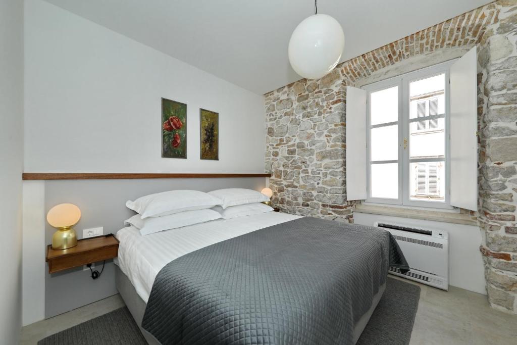 ein Schlafzimmer mit einem Bett und einer Ziegelwand in der Unterkunft Sidra Heritage in Zadar