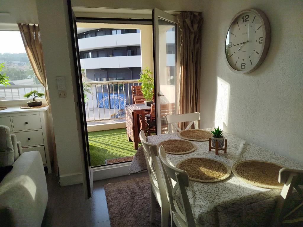a dining room with a table and a clock on the wall at Studio centre port,piscine et parking sous terrain in Cap d'Agde