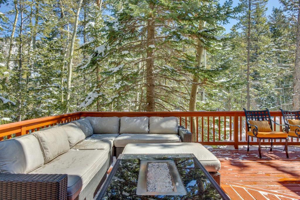 a couch and a table on a deck with trees at Idaho Springs Cabin with Hot Tub on Half Acre! in Idaho Springs