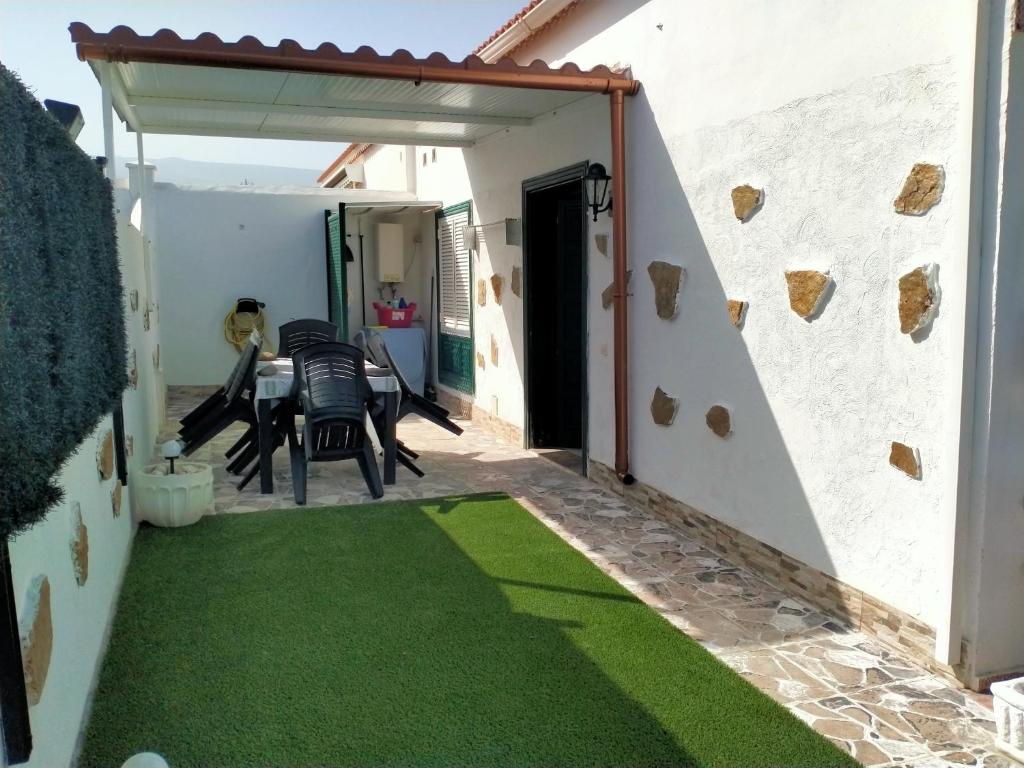 eine Terrasse mit grünem Gras sowie einem Tisch und Stühlen in der Unterkunft Villa Feliz in Abades