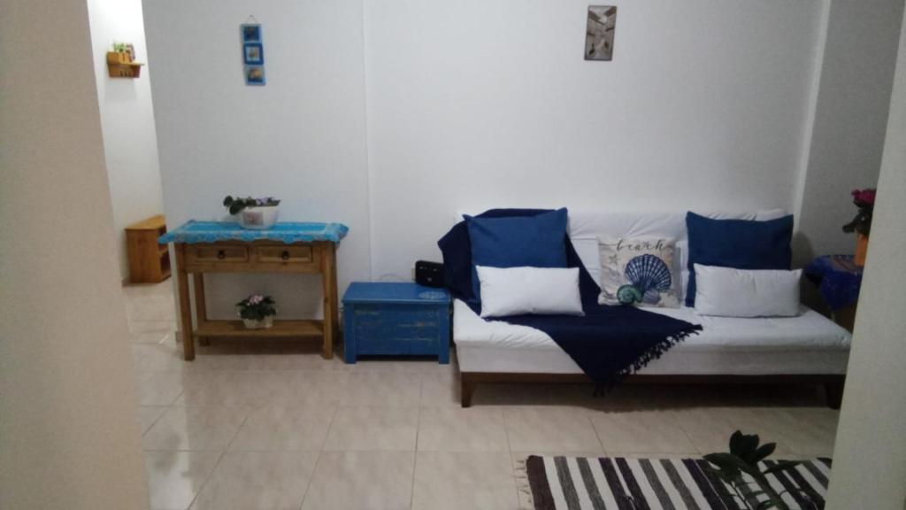 a living room with a couch with blue and white pillows at Apartamento Aconchegante 70m praia in Mongaguá