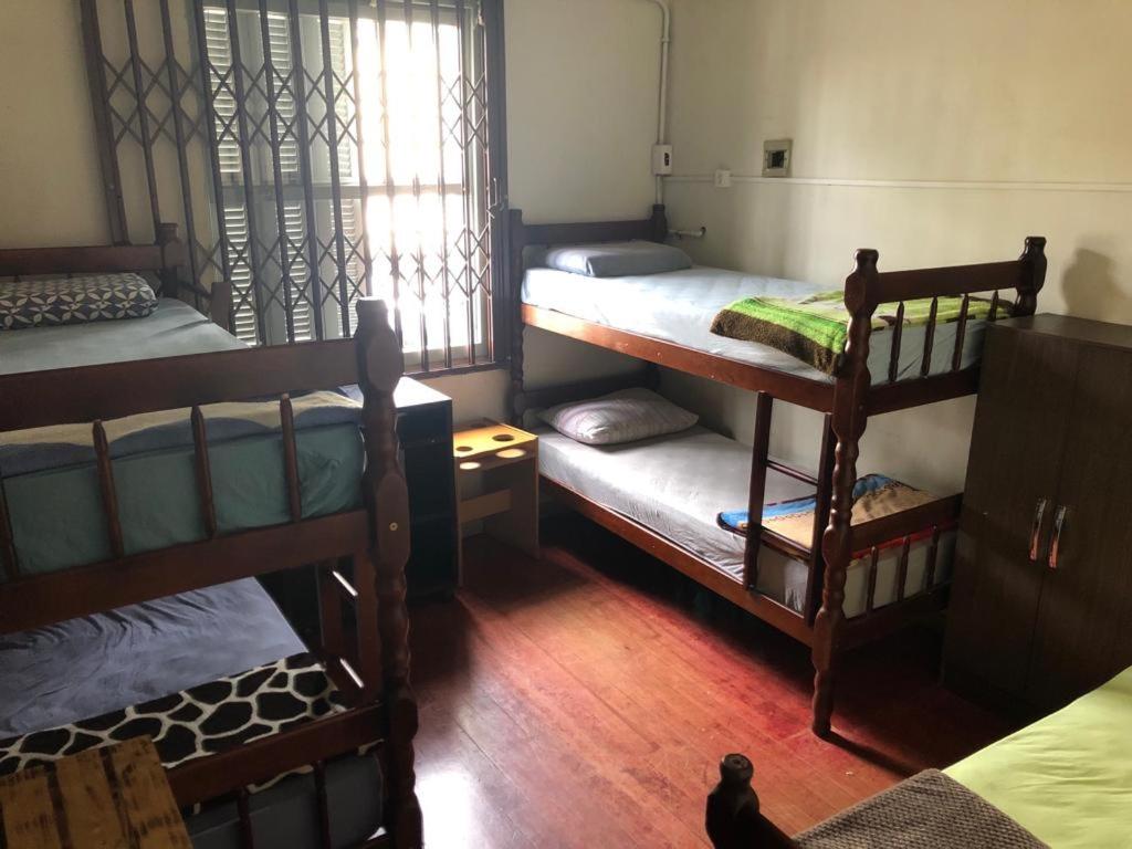 a room with three bunk beds and a window at Pensão da Su in Caxias do Sul