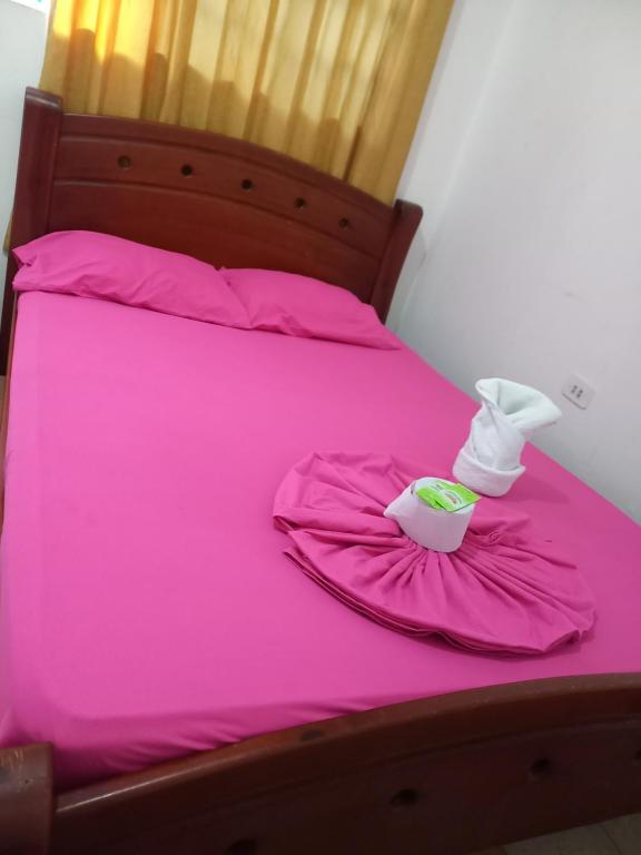 un lit rose avec des draps roses et une tasse dessus dans l'établissement Hotel Selecta, à Villavicencio