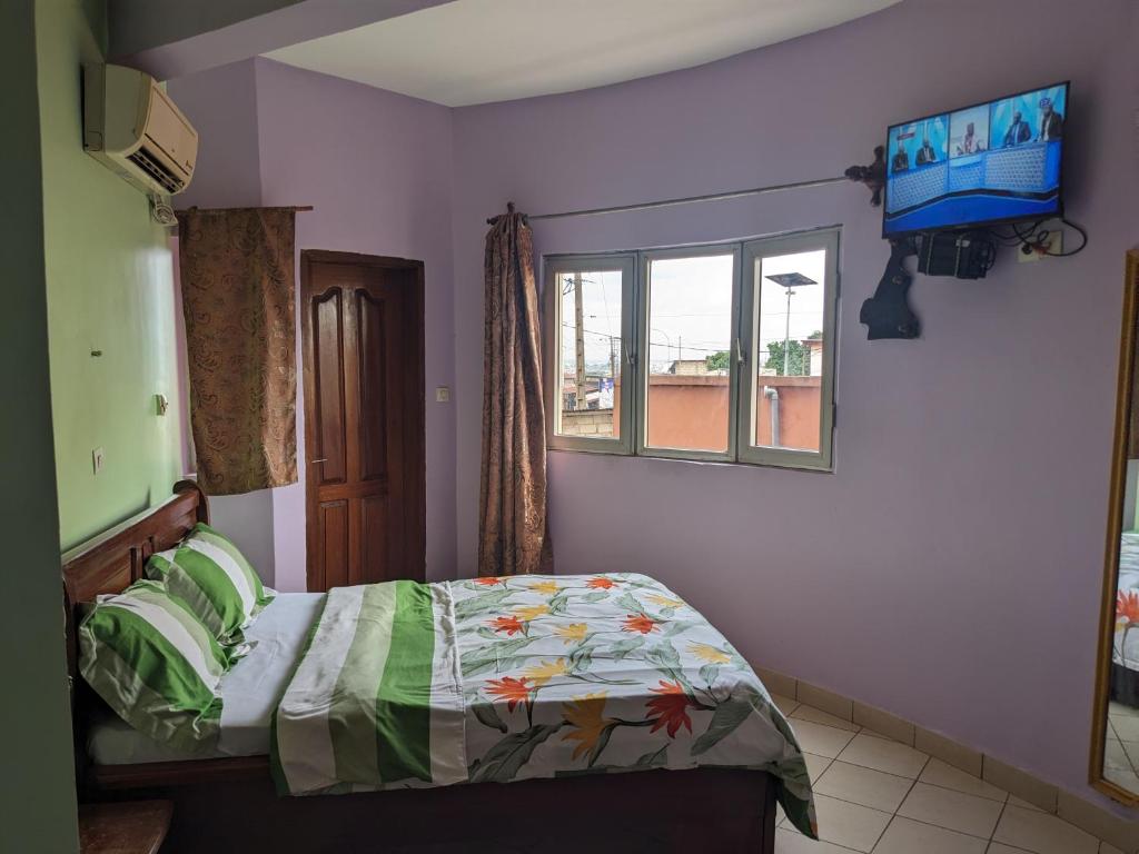 雅温得GRÂCES hôtel的一间卧室，墙上有一张床和一台电视