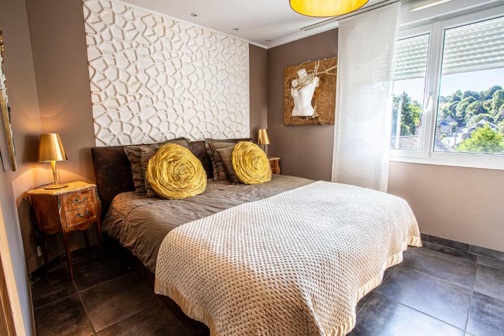 une chambre avec un lit avec des oreillers jaunes et une fenêtre dans l'établissement Maison Contemporaine Bien être Jacuzzi Hammam et Art immersif dans un cadre zen proximité Mont Saint Michel, à Saint-James