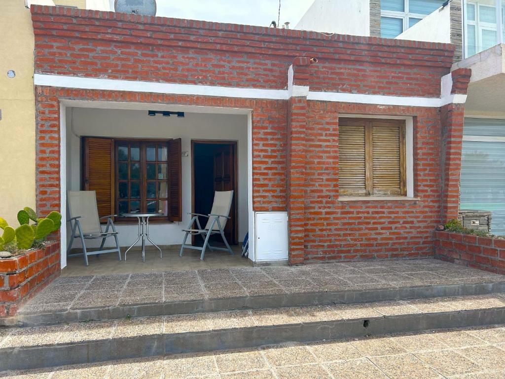 a brick building with a patio with chairs and a table at Lōla Beach House - Playa Unión in Playa Unión