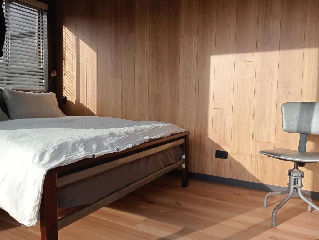a bedroom with a bed and a chair at Container Stay - Taupo in Taupo