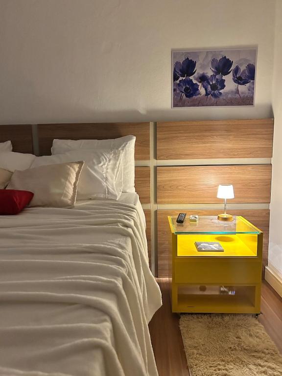 a bedroom with a bed and a yellow night stand at Nossa casa, nosso lar in Belo Horizonte