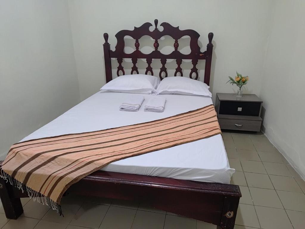 a bed with a wooden headboard and white sheets at Casa Aconchegante in Vitória da Conquista
