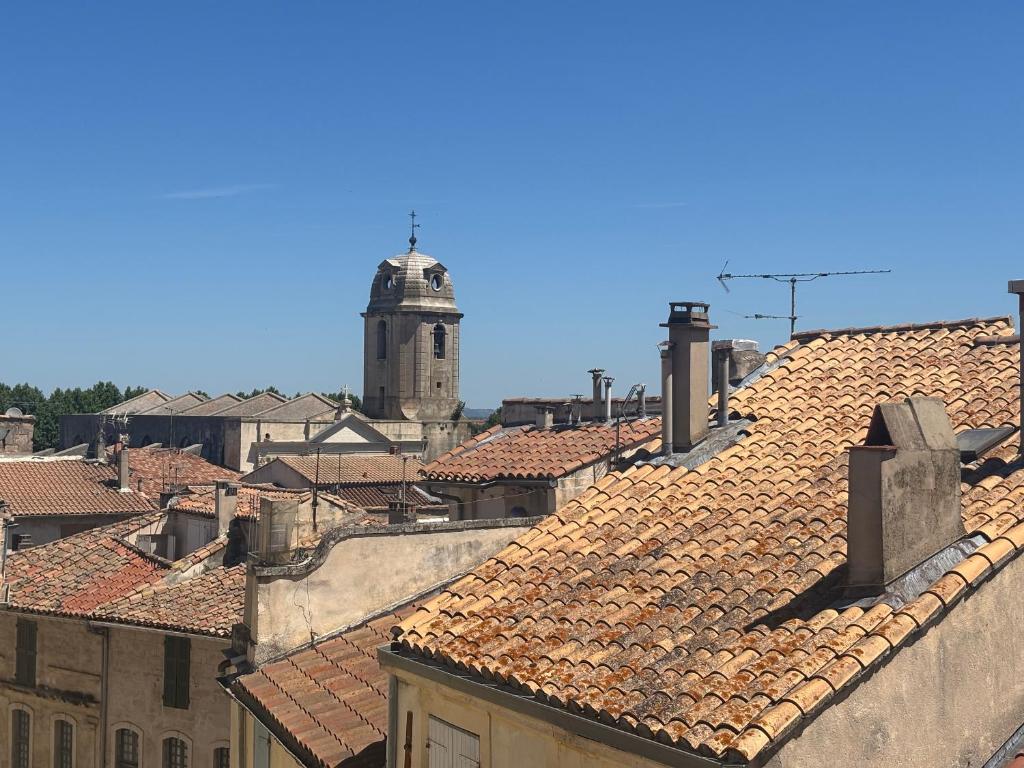 - une vue sur les toits d'une ville avec une tour d'horloge dans l'établissement ARLES: Duplex Chic Centre - Clim & Vue Imprenable - FR-1-765-29, à Arles