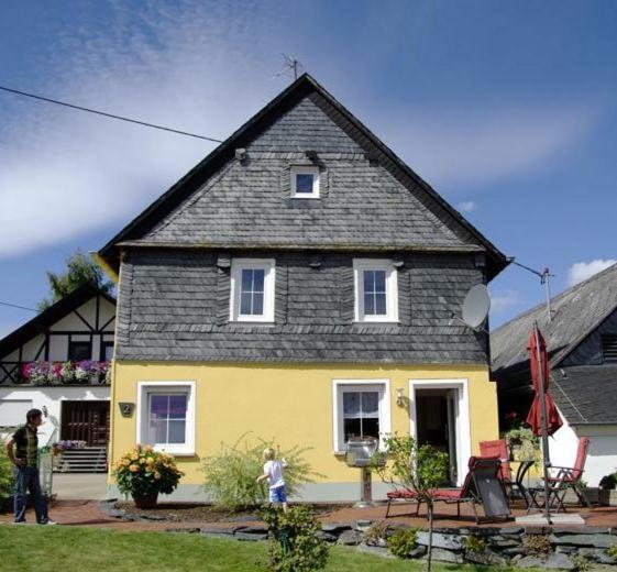 une maison jaune et noire avec une personne debout devant elle dans l'établissement Ferienhaus zur Altlayer Post, à Altlay