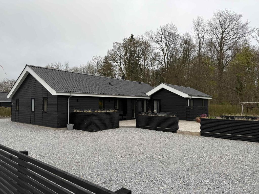 a black house with a fence in front of it at Modern Summer House In Pøt With Spa & Sauna in Sønderby
