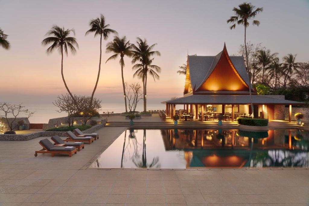 ein Resort mit Pool und einem Gebäude mit Palmen in der Unterkunft Chiva-Som International Health Resorts in Hua Hin