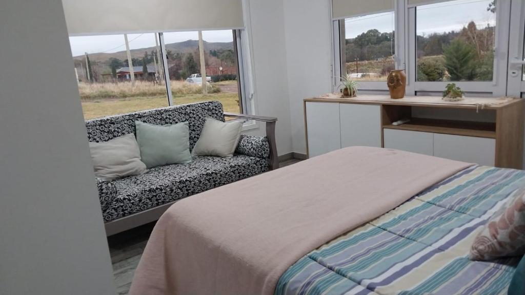 Un dormitorio con una cama y un sofá y una ventana. en Casitas de Ale en Sierra Ventana, en Sierra de la Ventana