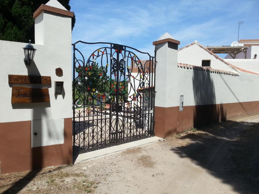 Un cancello in una recinzione con un albero dietro. di Domo Serra E Mesu a Magomadas